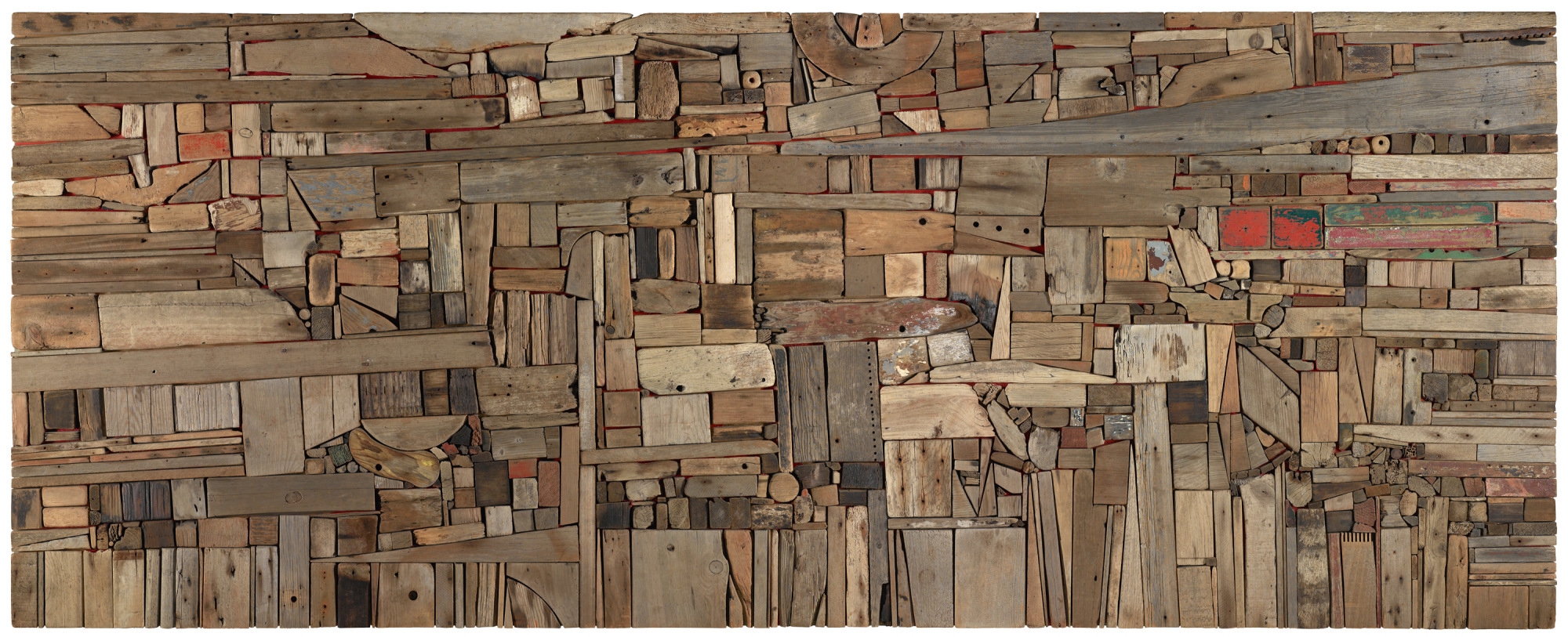 A flat abstract assemblage of wood pieces in various shapes, sizes, and colors fitted together perfectly like puzzle pieces.