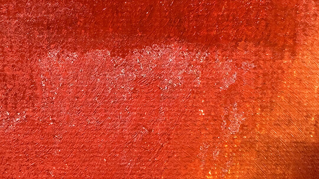 A close-up of what resembles white fuzz on the surface of a red painting.