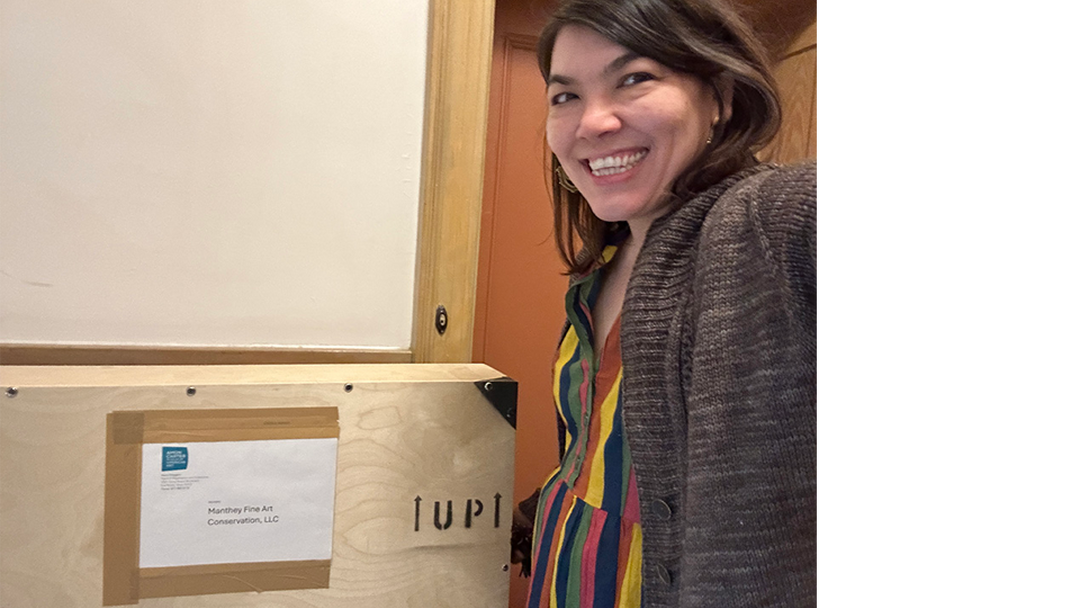 A smiling White woman stands next to a wood crate addressed to the Carter.
