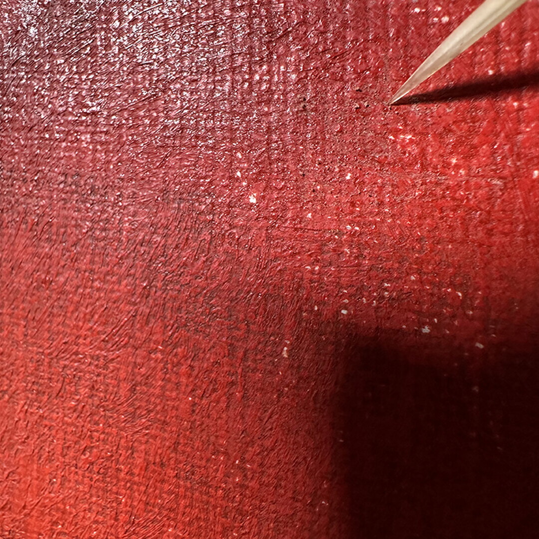 A close-up of the tip of a porcupine quill on the surface of a painting.
