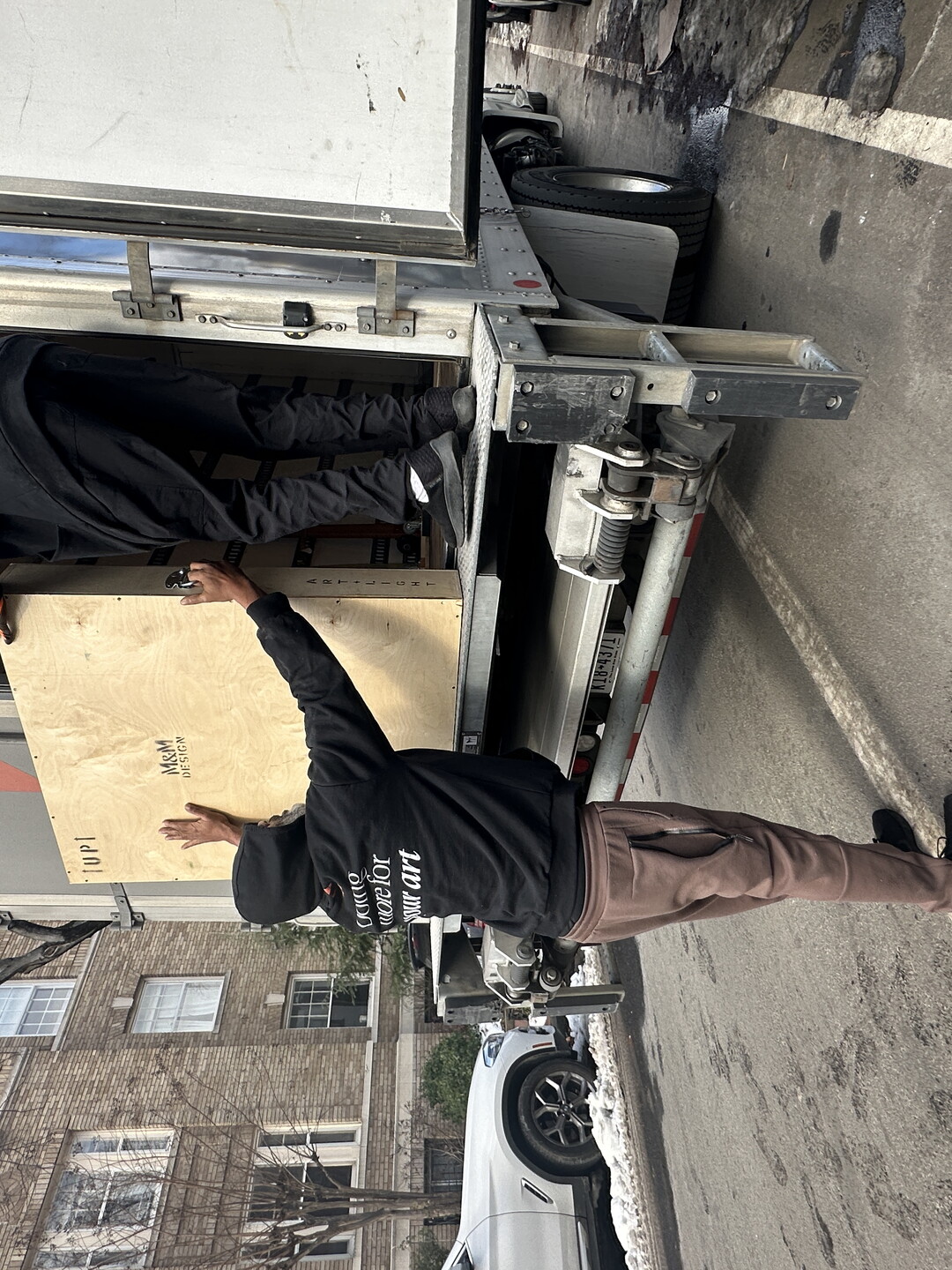Two people lift a wood crate onto a truck.