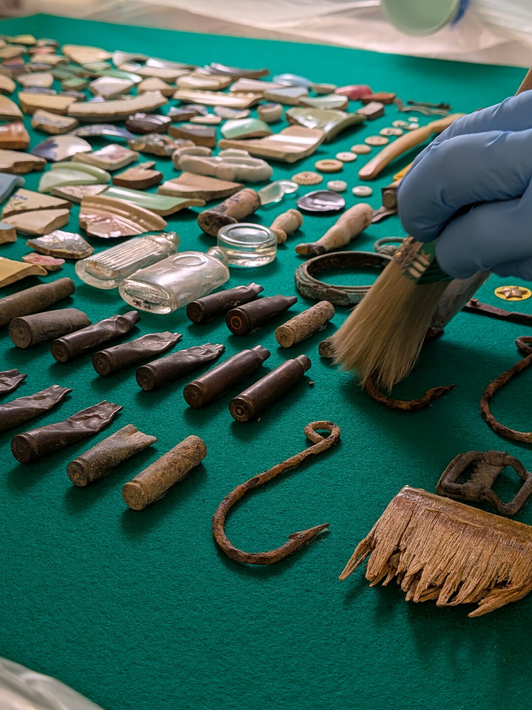 A close-up of a latex-gloved hand using a brush to clean the objects in the disinfection chamber.