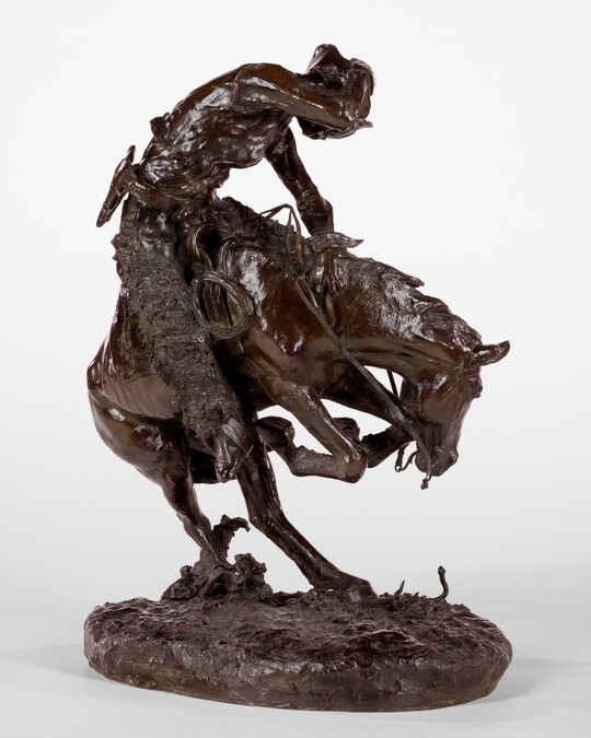 A sculpture of a man riding a bucking horse around a rattlesnake.