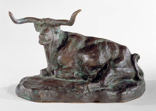 A bronze sculpture of a longhorn steer resting on the ground.