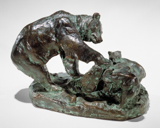A bronze sculpture of a bear and its cub pawing an upturned rock.