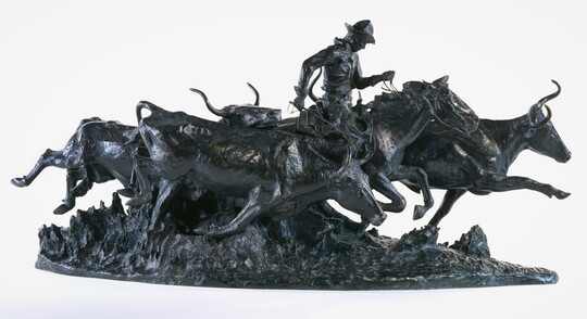 A bronze sculpture of a cowboy on a running horse surrounded by stampeding cattle.