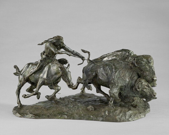 A sculpture of a Native American on horseback using a bow and arrow to hunt two bison.