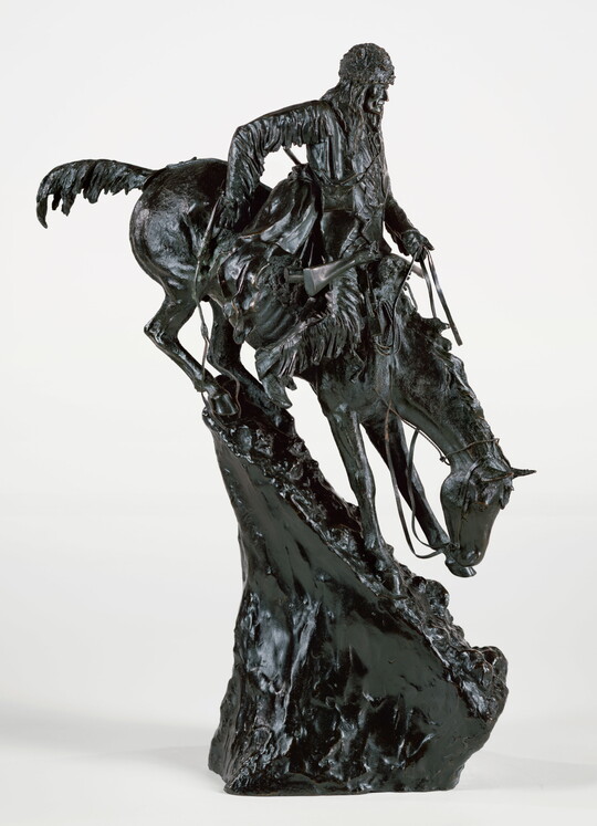 A bronze sculpture of a man going down a very steep mountain on horseback.