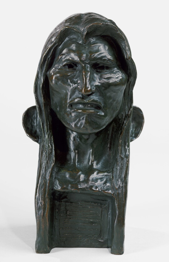 A bronze bust of an Indigenous man with long hair.