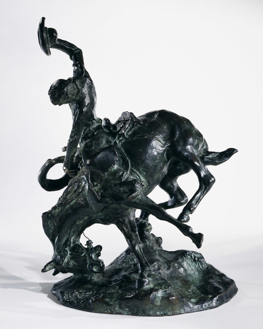 A bronze sculpture of a cowboy trying to ride a bucking horse.