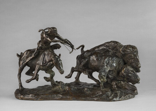 A bronze sculpture of a Native American on horseback hunting bison with a bow and arrow.A bronze sculpture of a Native American on horseback hunting bison with a bow and arrow.
