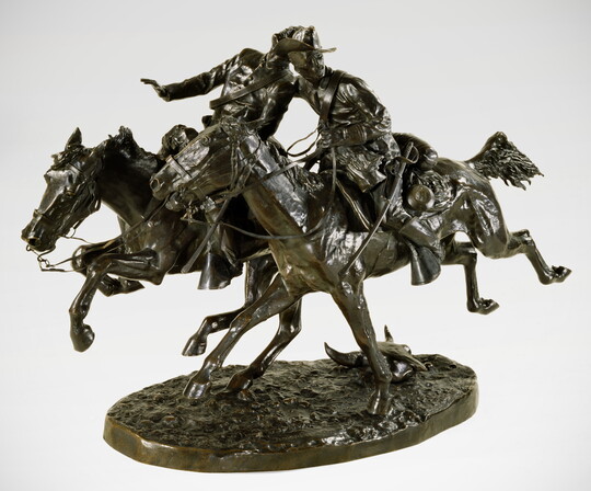 A bronze sculpture of two cowboys riding horseback side by side with one man wrapping his arm around the other in support.