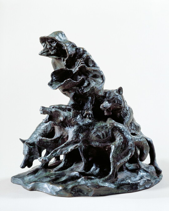 A bronze sculpture of an emaciated person wrapped in blankets surrounded by three snarling wolves.