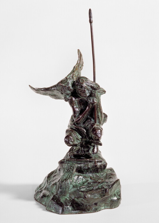 A bronze sculpture of a crouching Indigenous person holding a spear with a open-winged bird perched on their shoulder.