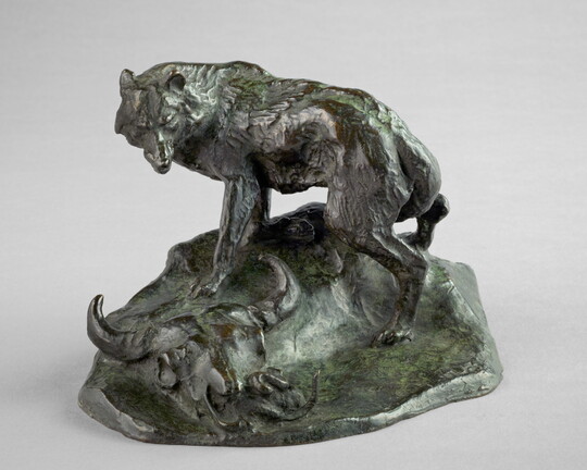 A bronze sculpture of a wolf standing over a bison skull with a rattlesnake hiding inside.