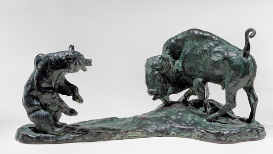 A bronze sculpture of a bison and a bear facing off.