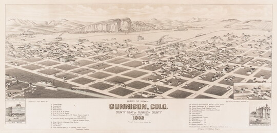 A black-and-white print of an aerial view of a town showing the grid of streets, railroad tracks, businesses, and homes with mountains in the background.