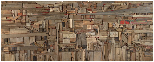 A flat abstract assemblage of wood pieces in various shapes, sizes, and colors fitted together perfectly like puzzle pieces.