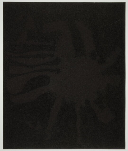 An abstract color print of a very dark brown splatter shape against a black background.