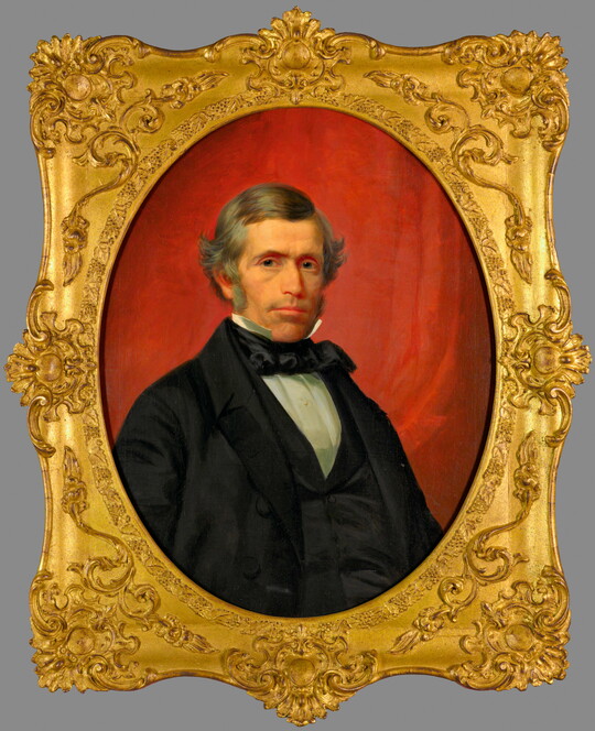 A portrait oil painting in a gold frame of a well-dressed White man with gray hair and sideburns.