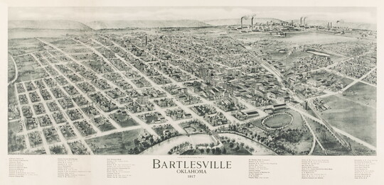 A black-and-white print of an aerial view of a city showing the grid of streets and factories in the distance.