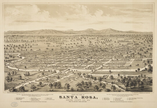 A sepia-toned print of an aerial view of a town with a grid of streets and mountains in the background.