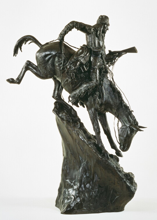 A bronze sculpture of an Indigenous man on horseback traveling down a steep mountain.