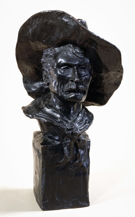 A bronze bust of a mustached man wearing a cowboy hat and a kerchief around his neck.