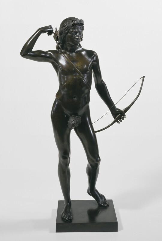 A bronze sculpture of a nude, male archer reaching for an arrow in the quiver on his back.