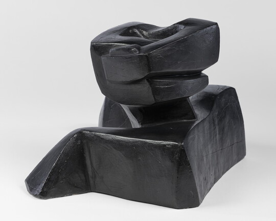An abstract, black sculpture resembling a figure's head and shoulders.