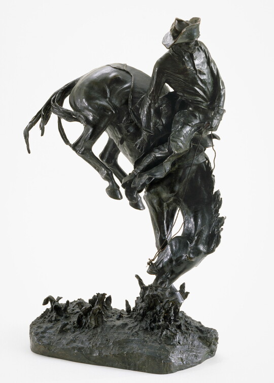 A bronze sculpture of a cowboy trying to stay on the back of a bucking bronco.