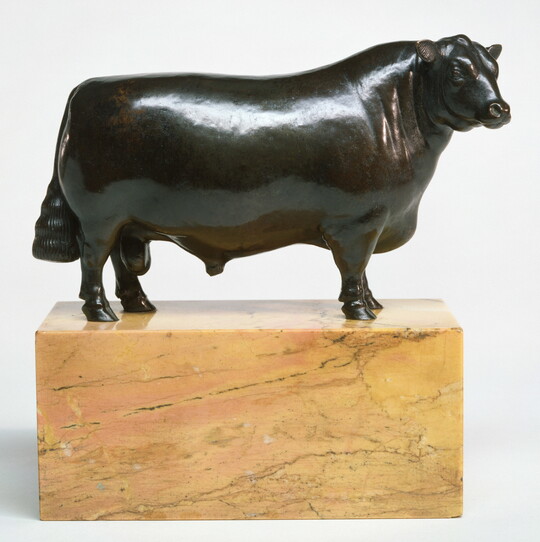 A bronze sculpture of a bull with a thick body and chest standing on a stone base.