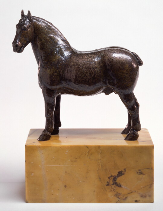 A bronze sculpture of a stallion with a bobbed tail standing on a stone base.