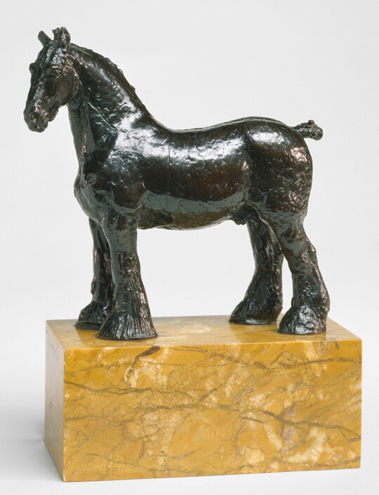 A bronze sculpture of a stallion with a bobbed tail and long hair on its legs below the knees standing on a stone base.