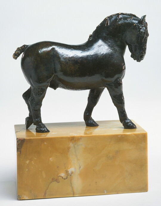 A bronze sculpture of a stallion with a braided mane on a base of yellow marble.