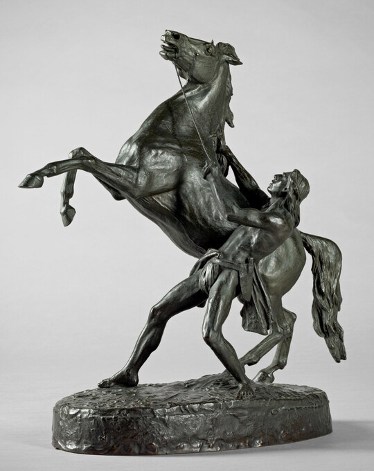 A bronze sculpture of a Native American man holding back a rearing horse.