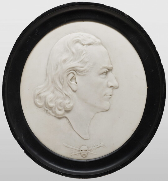 A marble cameo of a man in profile with shoulder-length wavy hair.