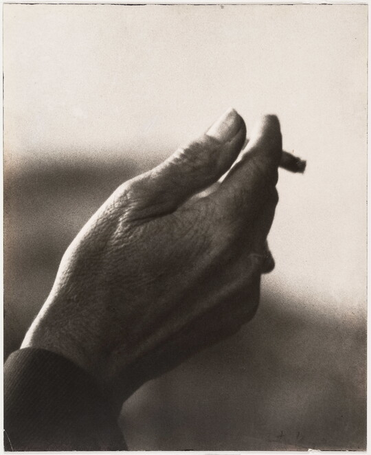 A sepia-toned close-up photograph of a right hand holding an almost-finished cigarette.