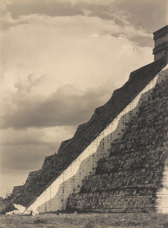 A black-and-white photograph of the diagonal corner edge of a Mayan step-pyramid.