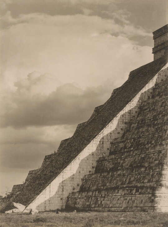 A black-and-white photograph of the diagonal corner edge of a Mayan step-pyramid.