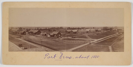 A sepia-toned panoramic photograph of a town with roads and buildings.