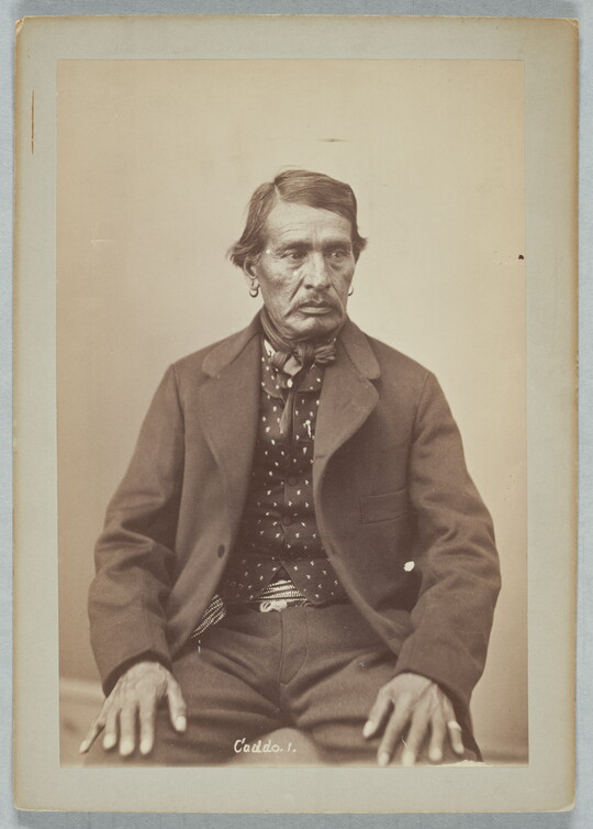 A sepia-toned portrait photograph of a man wearing an open jacket, patterned shirt, and a bowtie.