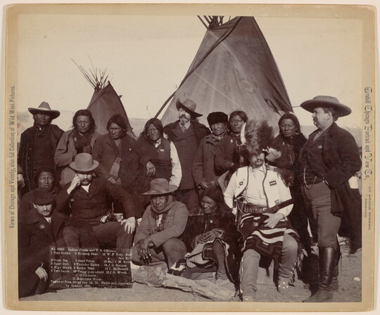 A black-and-white photograph of Indigenous men and U.S. officials in front of tipis.