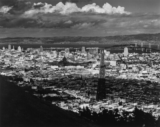 A black-and-white photograph of an arial view of San Francisco, parts of which are in shadow from clouds.