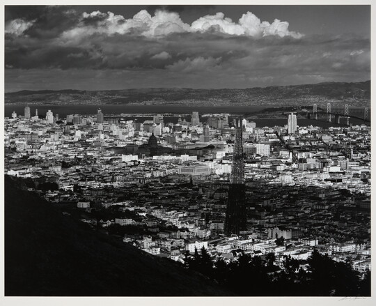 A black-and-white photograph of an arial view of San Francisco, parts of which are in shadow from clouds.