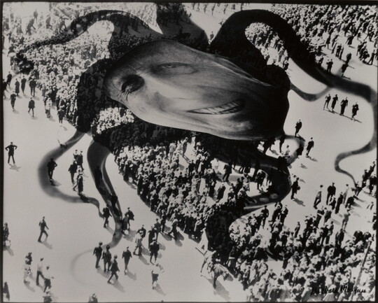 A black-and-white photograph of a distorted face superimposed over the shadow of an octopus hovering above a crowd of people.