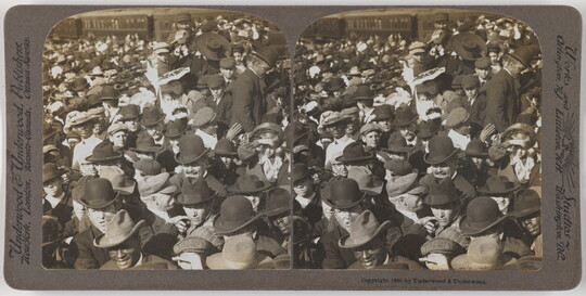 Two almost identical side-by-side black-and-white photographs of a large crowd of people, most wearing hats.
