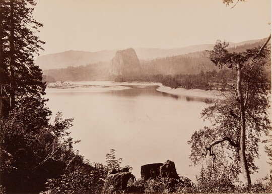 A sepia-toned photograph of a serene river surrounded by trees, rock formations, and mountains.