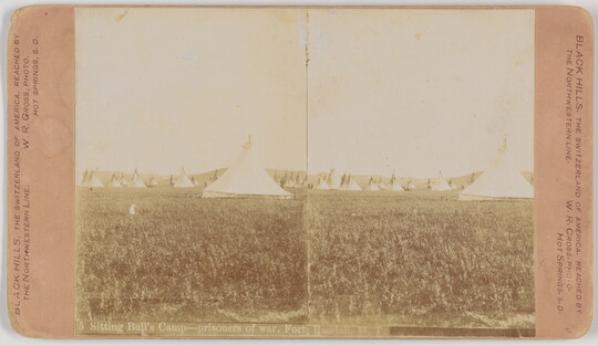 A sepia-toned stereograph of multiple tipis on a grassy field.
