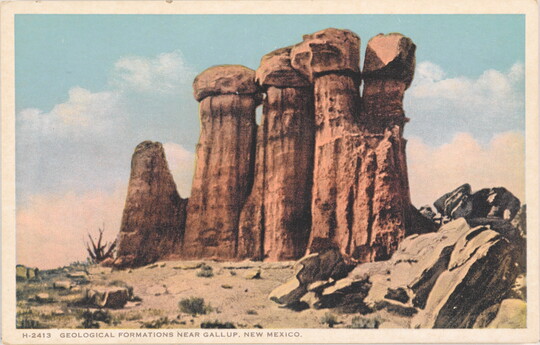 A color postcard of a tall rock formation in a desert landscape.